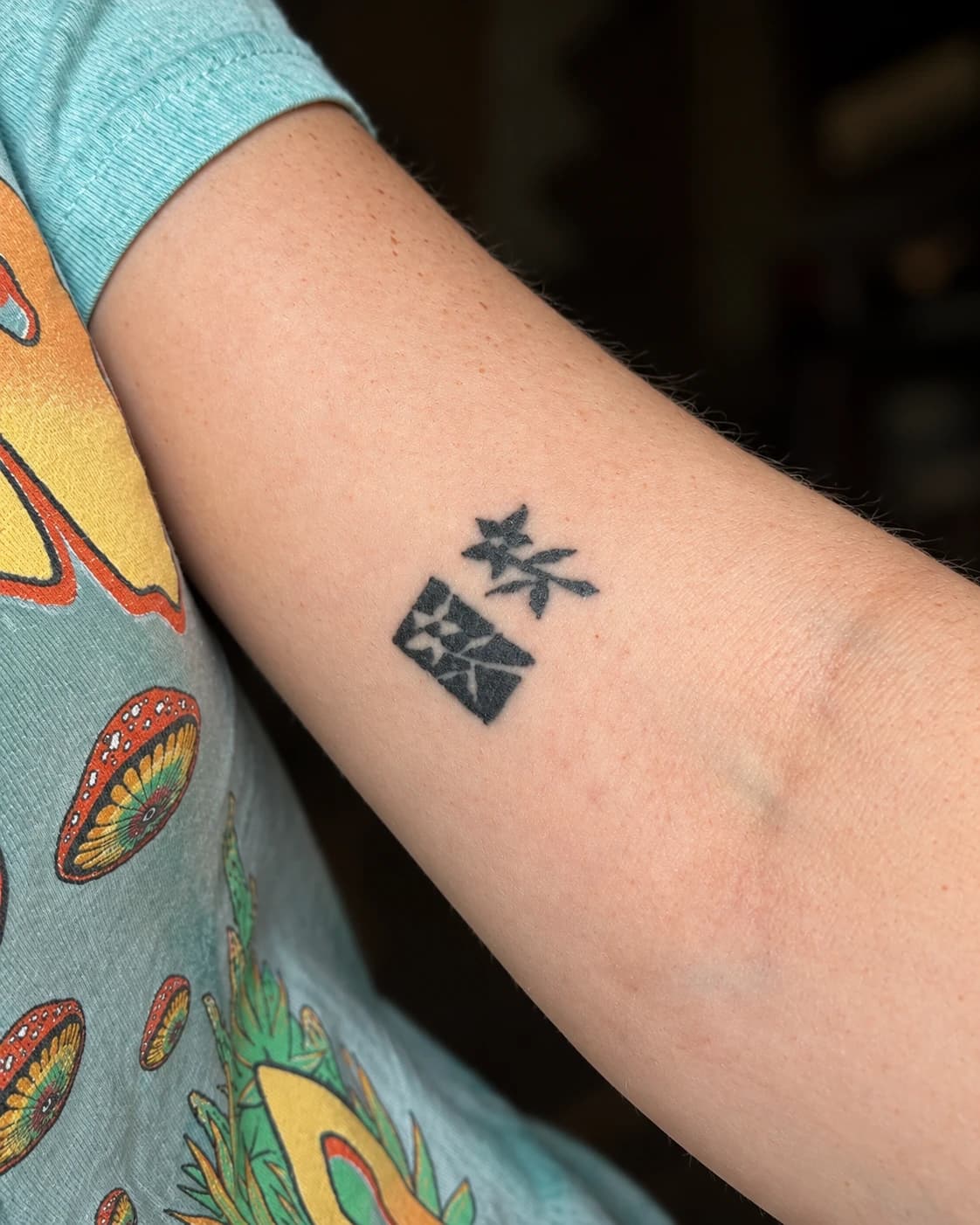 Small black graphic symbols tattooed on the inside of an arm